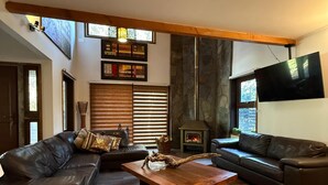 Ein modernes Wohnzimmer mit zwei Ledersofas, einem Holztisch und einem Kamin.