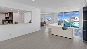 A spacious living area with a modern kitchen, a dining area, and a large window offering a city view. - Oceanview Penthouse Pool Beach Access (Hollywood)