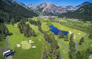 Ein Golfplatz mit einem See, umgeben von Bergen und dichten Wäldern.