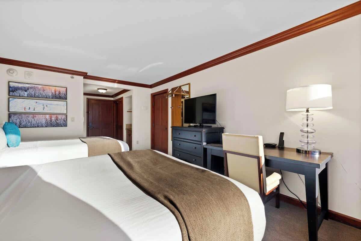 Une chambre d’hôtel avec deux lits, un bureau, une télévision et une lampe.