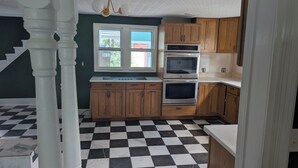Eine Küche mit Holzausstattung, einem Doppelbackofen und einem karierten Boden.