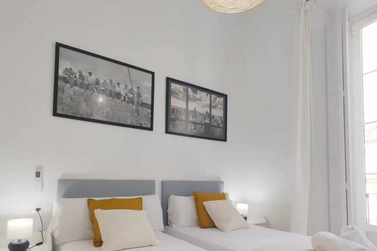 Habitación de hotel con dos camas, ropa de cama blanca y una fotografía de un paisaje urbano en la pared.