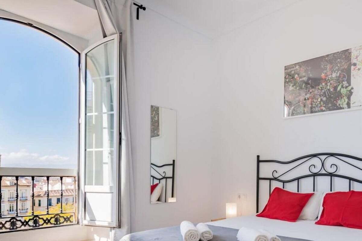 Una habitación de hotel con cama, ventana con vistas y un cuadro en la pared.