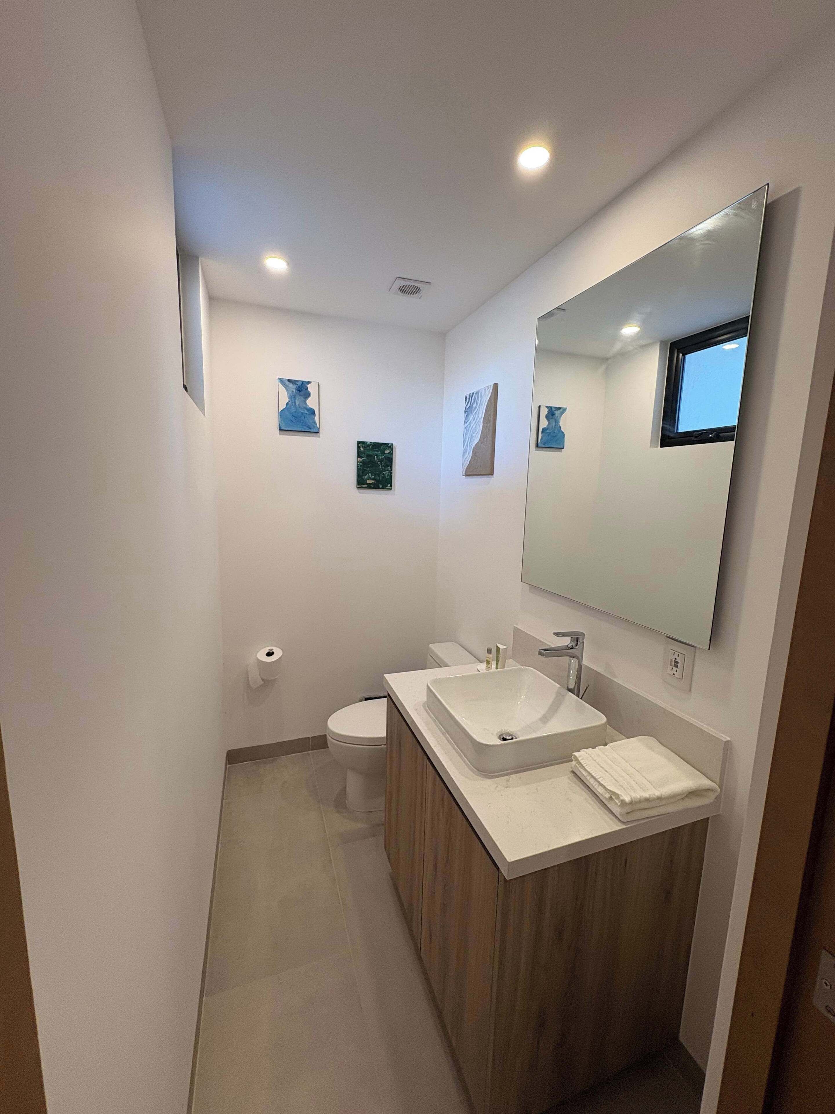 Ein modernes Badezimmer mit einem großen Spiegel, zwei Waschbecken und einer Toilette.