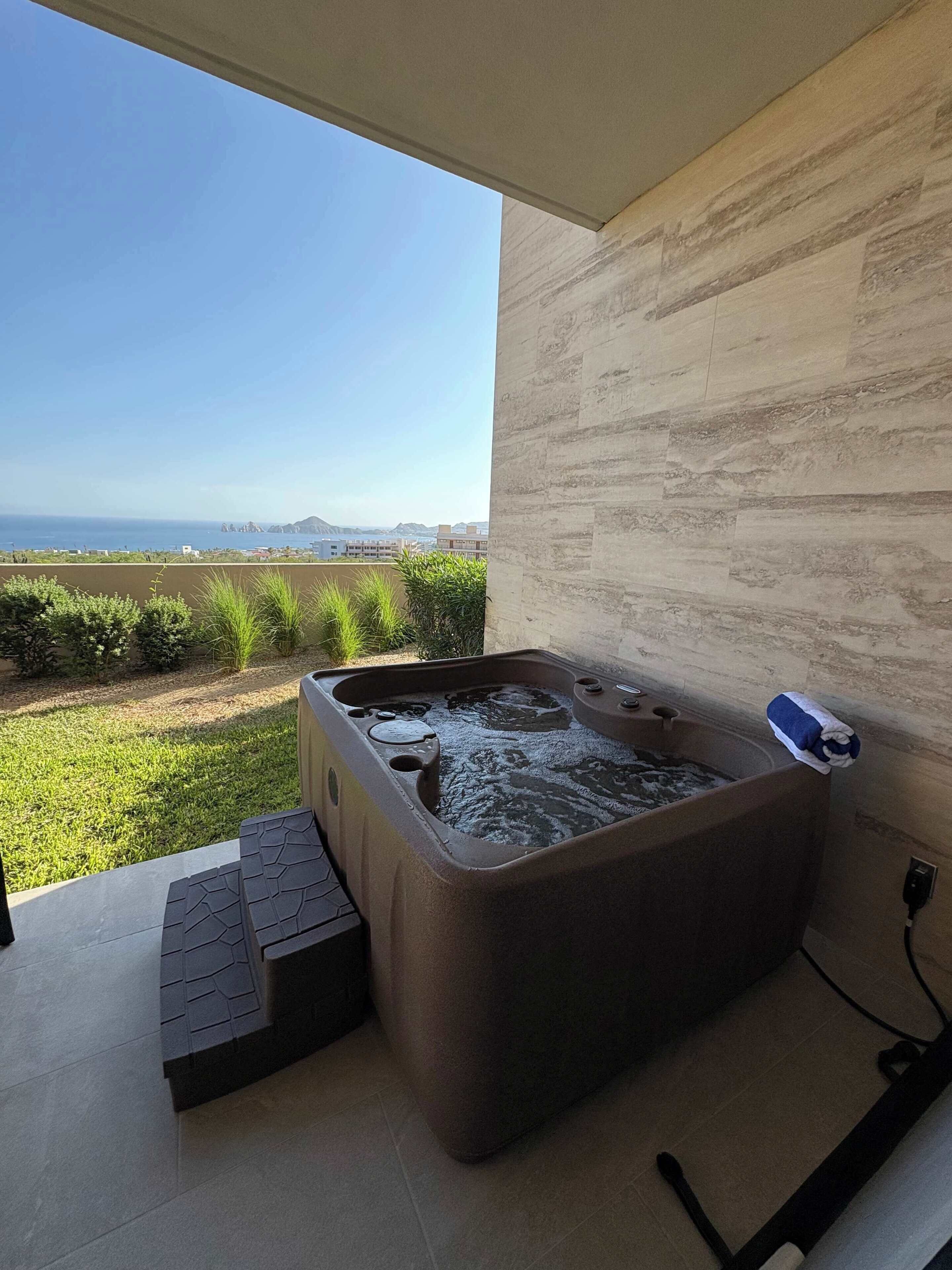 A hot tub on a balcony with a view of the sea and distant mountains.