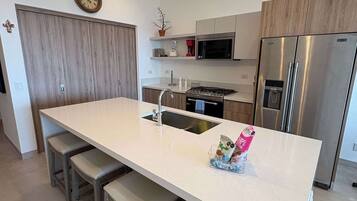 A modern kitchen with a central island, stainless steel appliances, and pendant lighting.