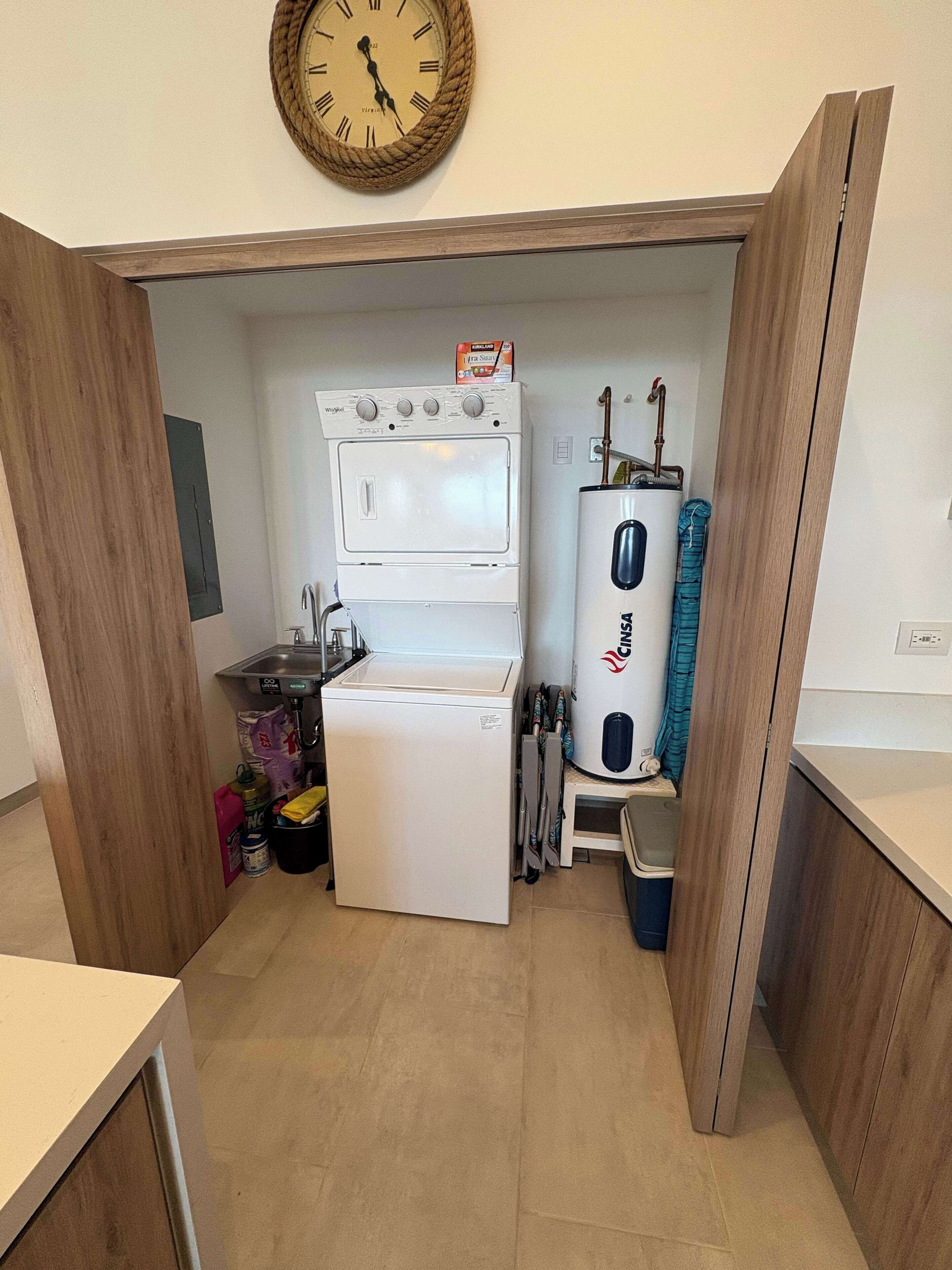 A compact kitchen with a washing machine, a refrigerator, a sink, and a water heater.