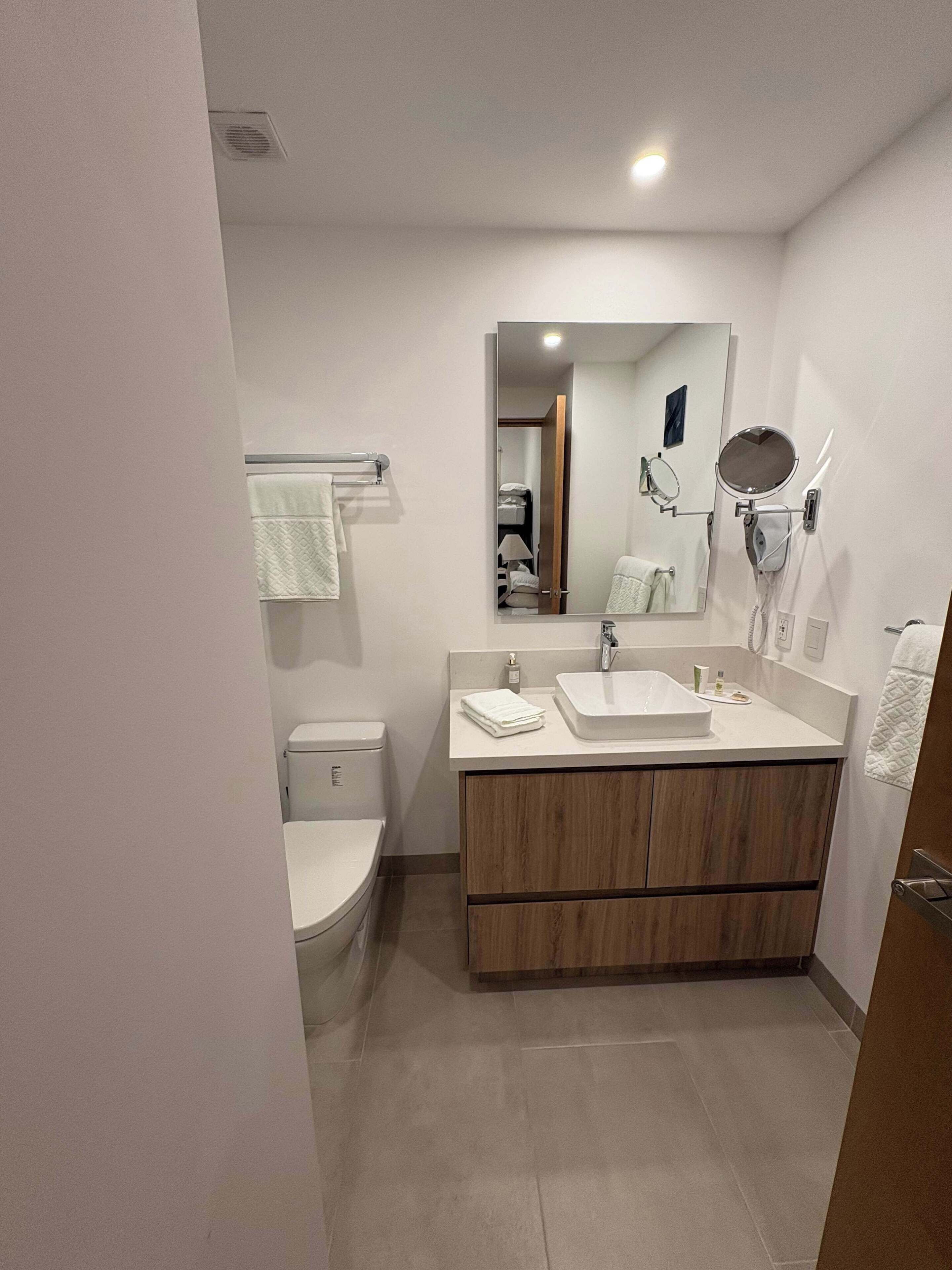 Un bany modern amb vàter, un lavabo, un mirall i un assecador.