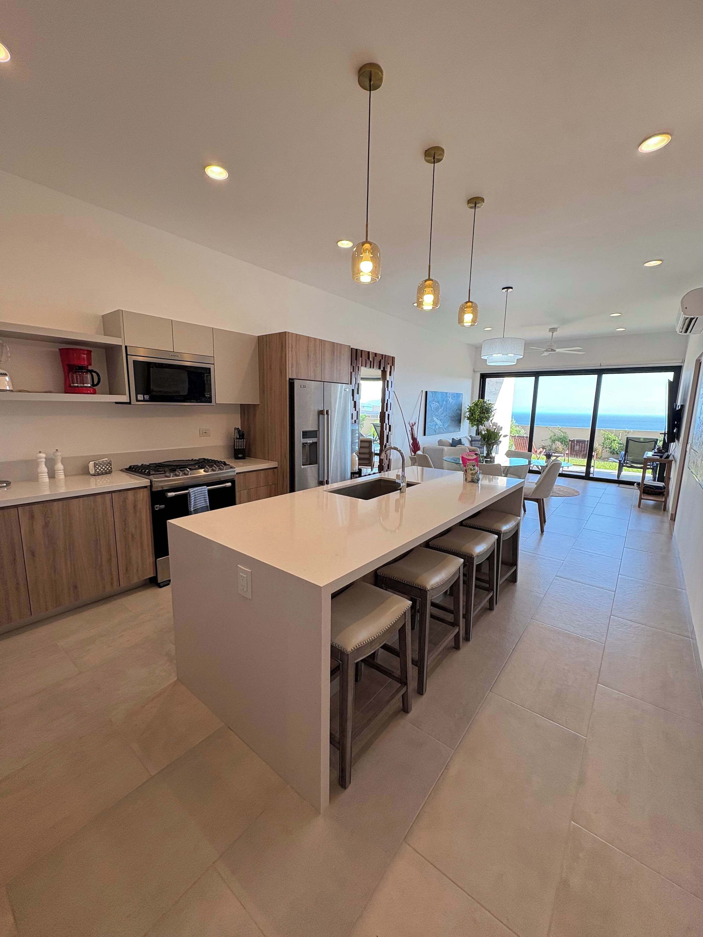 A modern kitchen with a central island, stainless steel appliances, and pendant lighting.