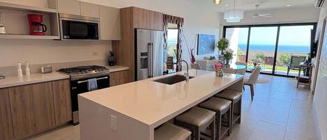 A modern kitchen with a central island, stainless steel appliances, and pendant lighting.