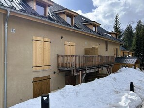 Ein Gebäude mit Holzläden, einem Balkon und verschneitem Grund.