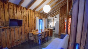 Ein Holzinterieur mit Essbereich, einem an der Wand montierten Fernseher und einer Sitzgruppe.