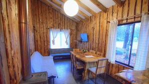 Ein rustikaler Holzraum mit Esstisch, Stühlen, einer Couch und einem Fernseher.