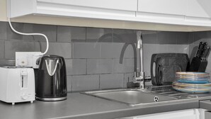 A modern kitchen with a built-in dishwasher, a coffee maker, and a sink. - Peaceful Kent Stay with Garden & Parking (Dartford)
