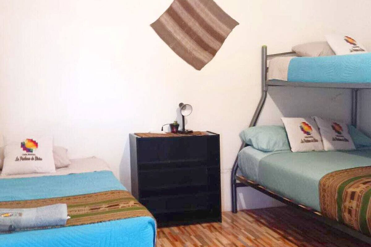 Ein Zimmer mit zwei Betten, einem Nachttisch und einem an der Wand befestigten Kissen.