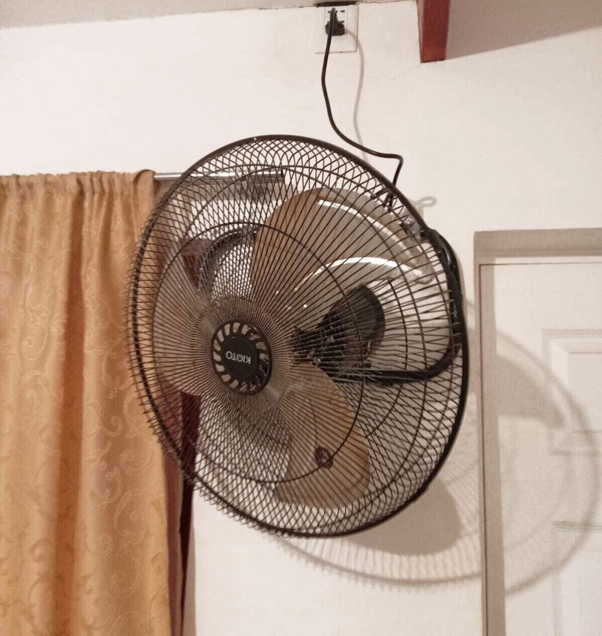 A standing fan with a visible brand name, mounted on a wall.