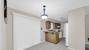 Eine geräumige Küche mit einer zentralen Kochinsel, weißen Schränken und einem Deckenventilator.