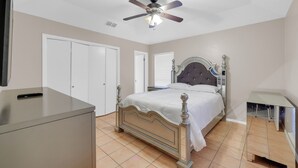 Ein Schlafzimmer mit Bett, Deckenventilator, Kleiderschrank und Schreibtisch.