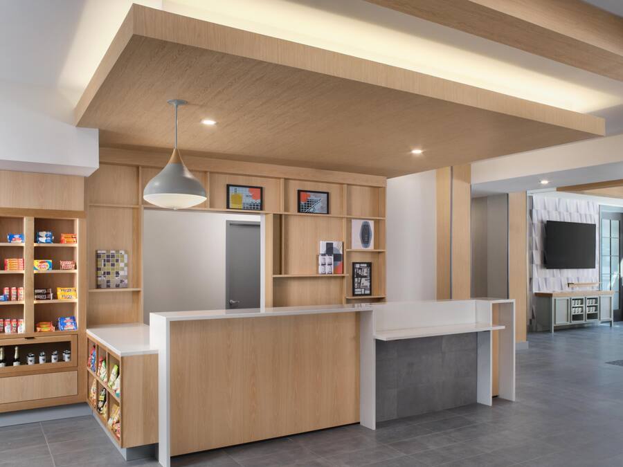 A reception desk with a wooden finish, a pendant light, and a wall-mounted TV.