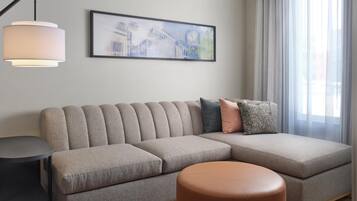 A modern living room with a sectional sofa, a round ottoman, a side table, and a wall-mounted lamp.