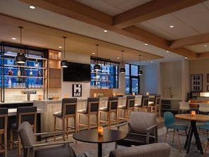 A bar area with wooden bar counters, multiple seating options including bar stools and chairs, and a television mounted on the wall. - Hyatt House Schenectady / Mohawk Harbor (Schenectady)