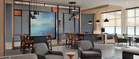 Un moderno vestíbulo de hotel con bar, zona de estar y grandes ventanales.