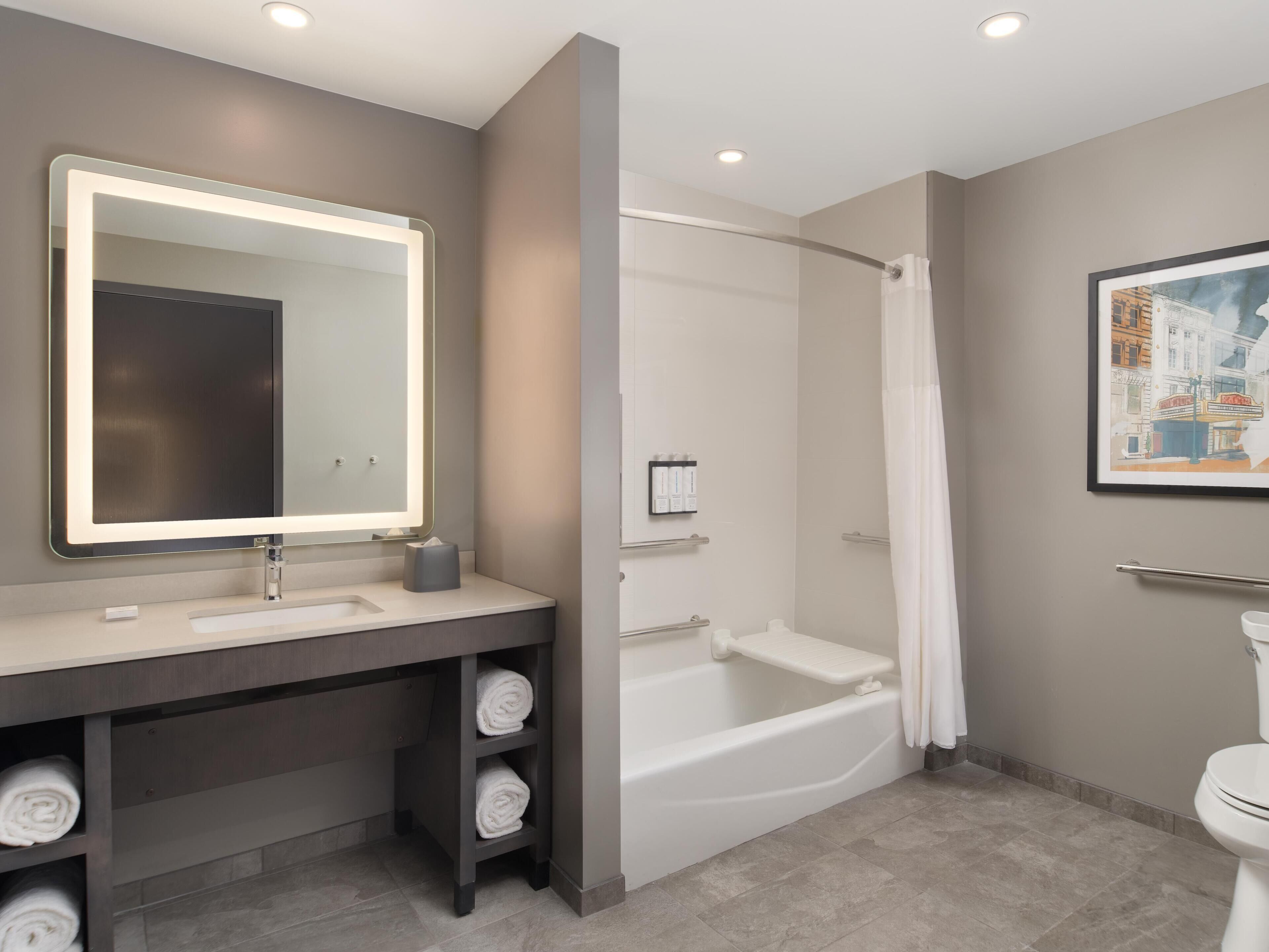 Un bagno moderno con uno specchio grande, una vasca da bagno, un water e un porta asciugamani.