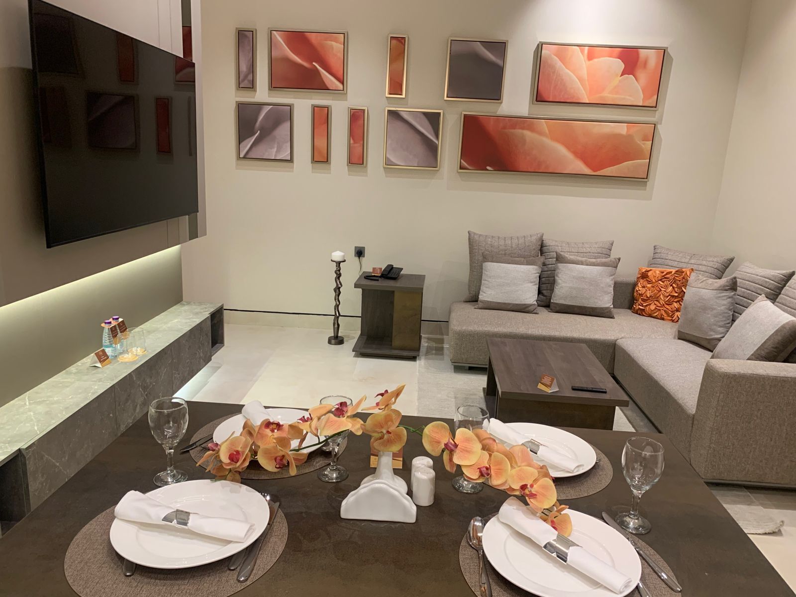 A modern living room with a sofa, coffee table, and a dining area set for four.