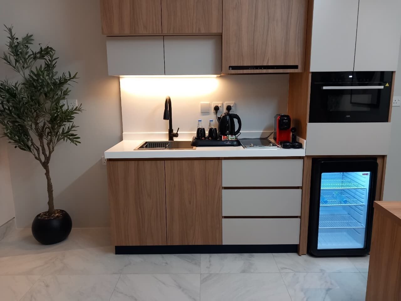 Een moderne keuken met houten kasten, een inbouwoven en een minibar.