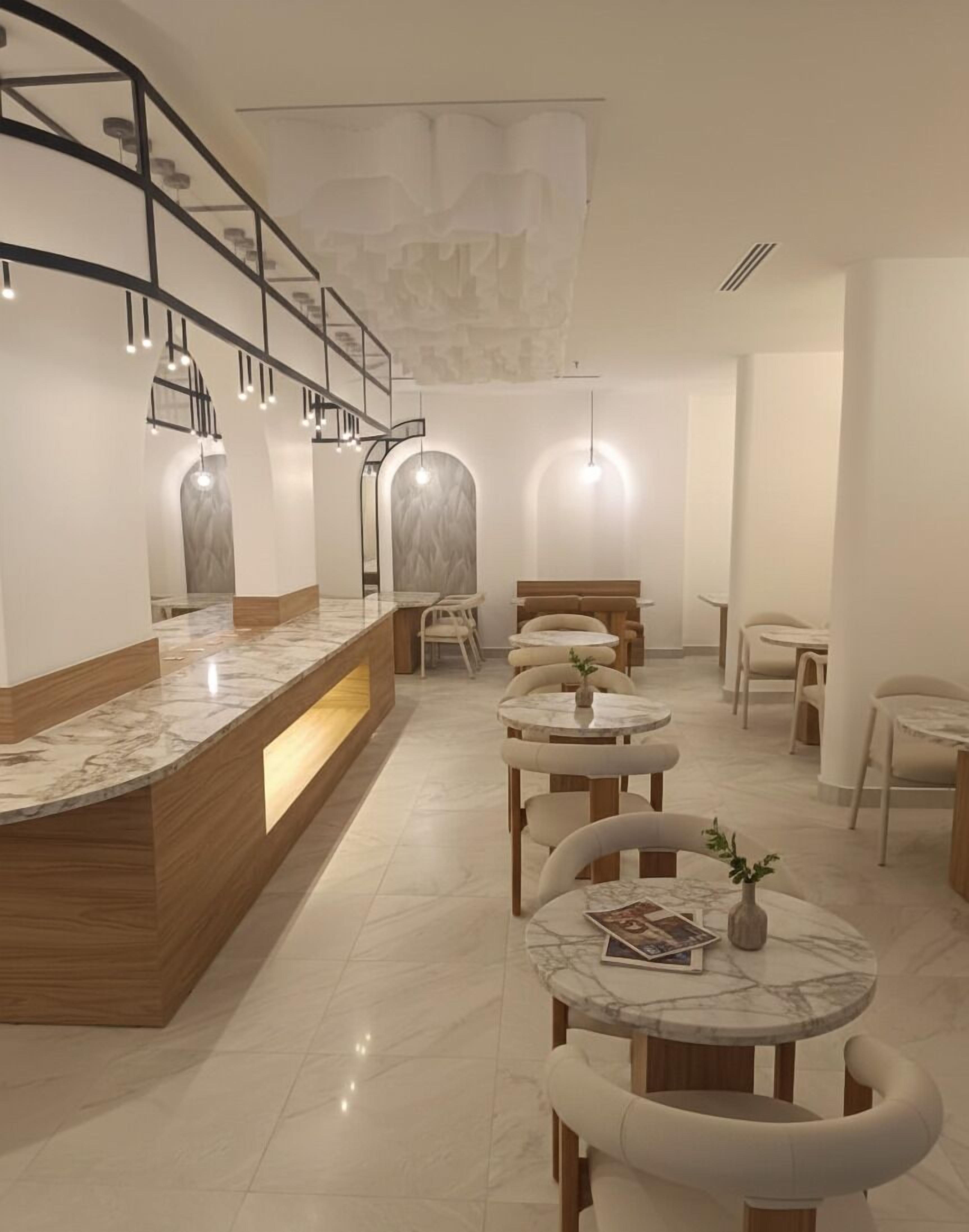 Un intérieur moderne avec un comptoir d’accueil en marbre, des éléments décoratifs en bois et des tables rondes accompagnées de chaises.