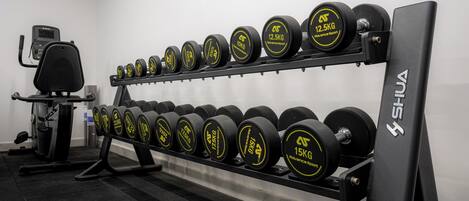 Une salle de sport équipée d’un support à poids avec des haltères de différents poids.