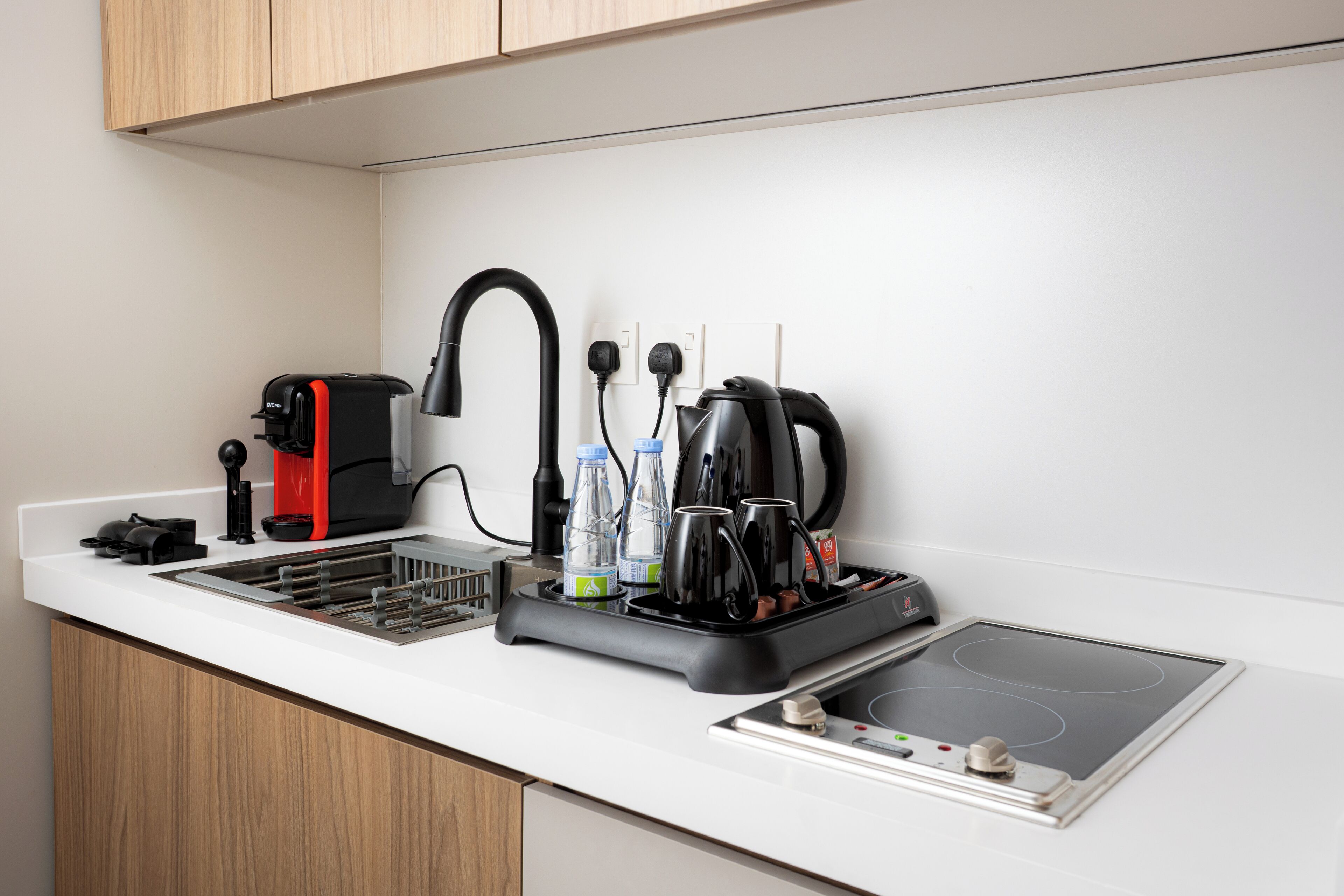 A modern kitchen with a built-in stovetop, a coffee maker, and a kettle.