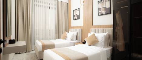 A hotel room with two beds, a desk, a mirror, and a wardrobe.