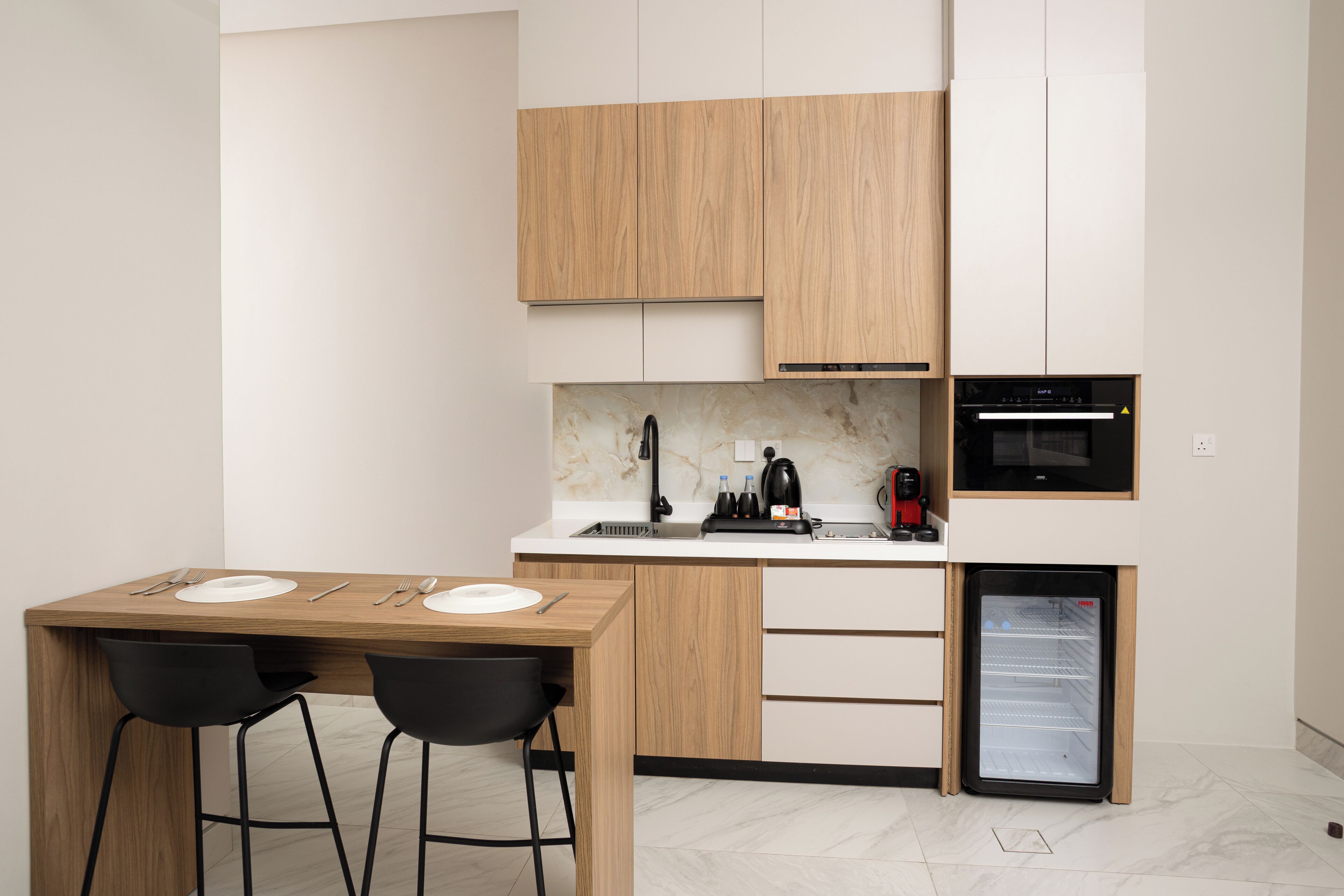 A compact kitchen with wooden cabinets, a built-in microwave, and a mini-fridge.