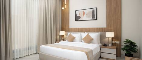 Una habitación de hotel moderna con una cama grande, dos mesitas de noche con lámparas, un aparador con un teléfono y una taza, una obra de arte abstracta enmarcada en la pared y una planta en maceta.