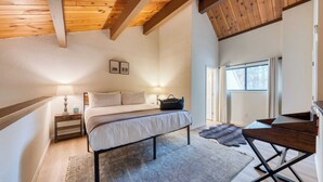 Een slaapkamer met een bed, nachtkastjes, een bureau en een raam.
