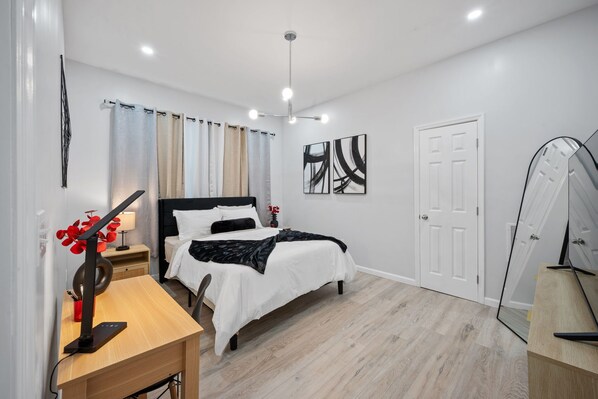 A modern bedroom with a bed, bedside table, lamp, and artwork. - Cocoa - Springfield Brand NEW Apt! (Jacksonville)