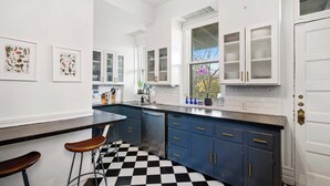 Una cocina moderna con piso a cuadros, armarios blancos y una barra.