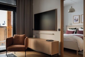 Ein modernes Schlafzimmer mit Bett, Schreibtisch, Stuhl und einem großen Fernseher.