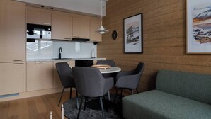 Una cocina moderna con armarios de madera, una zona de comedor con una mesa redonda y sillas, y un sofá verde.