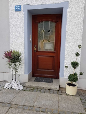 A wooden front door with a glass panel, a small potted plant to the right, and a number '22' sign above it. - Müllers Monteurunterkunft Gangkofen (Gangkofen)