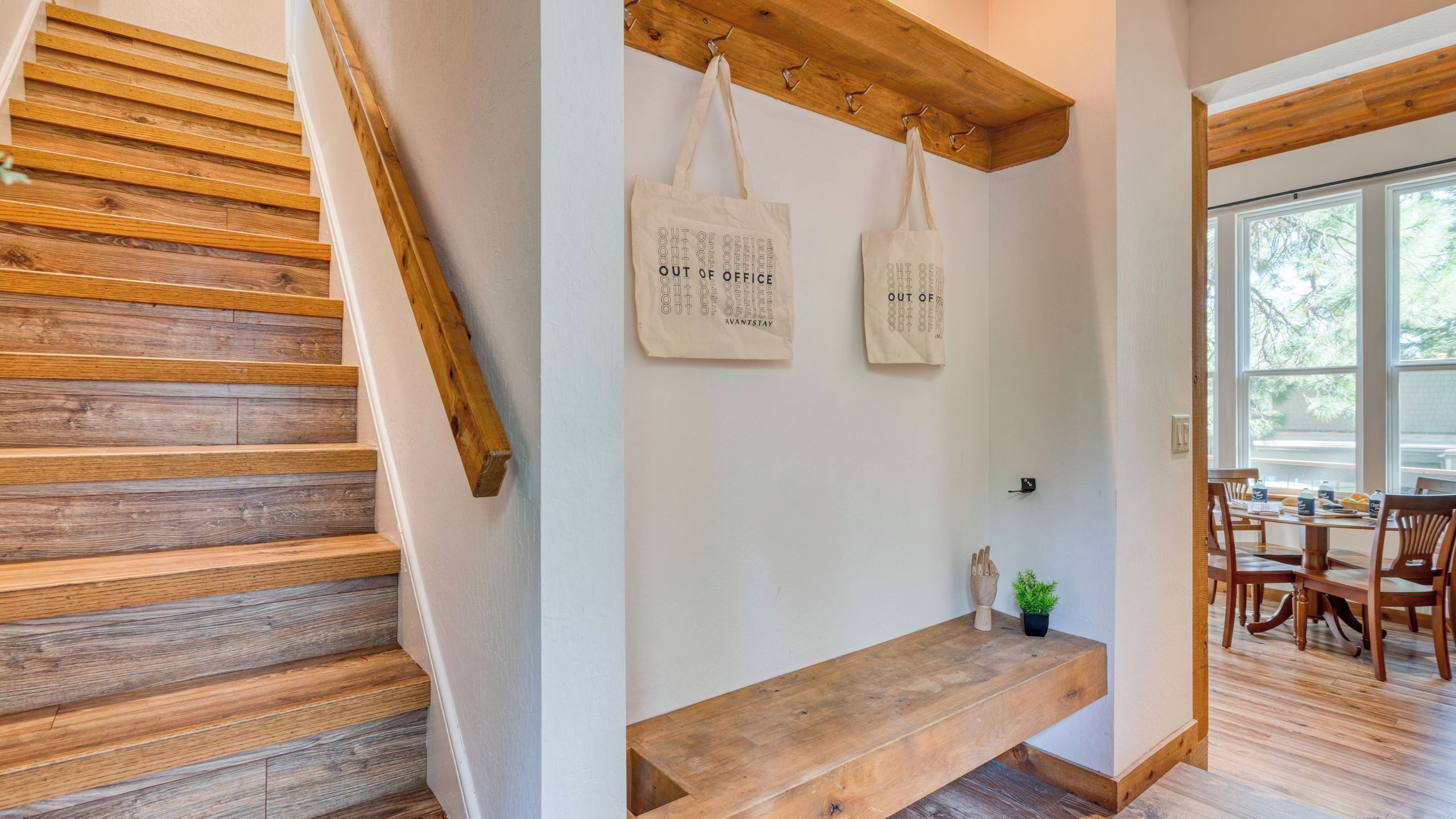 Un escalier en bois mène à un banc sur lequel sont suspendus deux sacs à provisions à une poutre en bois.
