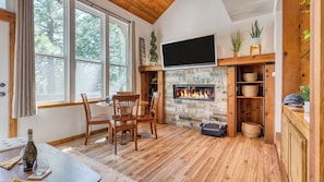 A cozy room with a fireplace, wooden furniture, and a television mounted on the wall.
