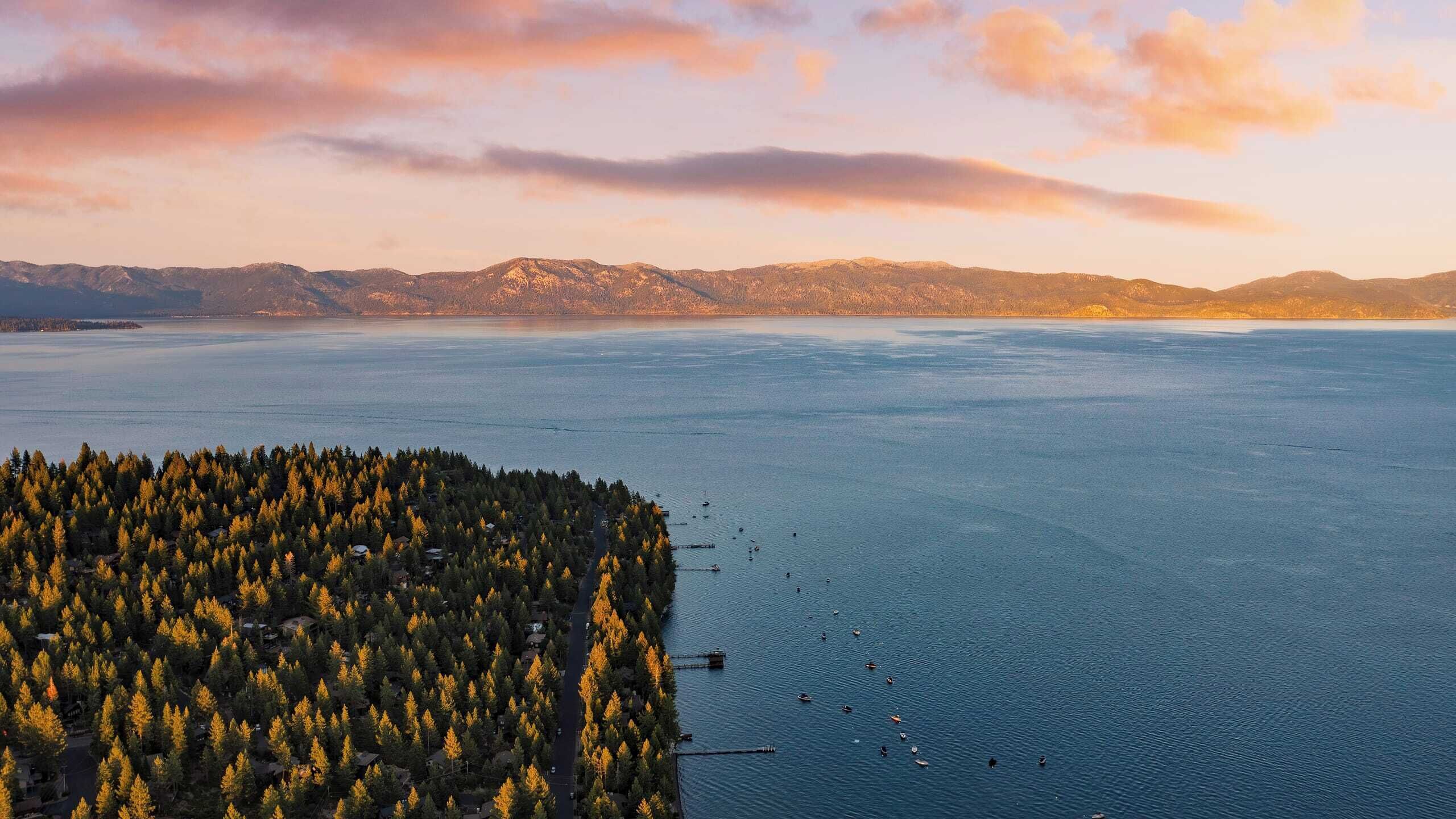Una vista panorámica de un lago con una isla boscosa en primer plano y montañas al fondo.