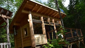 A wooden cabin with a balcony and a small deck. - Disconnect on a private estate, hiking trails, Finnish sauna, canoe,,,, (Saguenay)