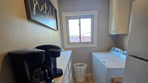 Een kleine keuken met een koffiezetapparaat, een wasmachine en een koelkast.