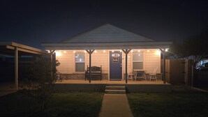 Een huis met een veranda, een blauwe deur en een bankje.