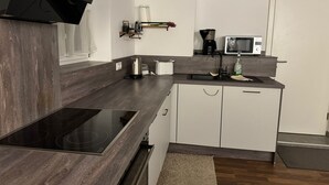 Eine moderne Küche mit dunkler Holz Arbeitsplatte, weißen Schränken, einem eingebauten Herd, einer Mikrowelle und einer Kaffeemaschine.