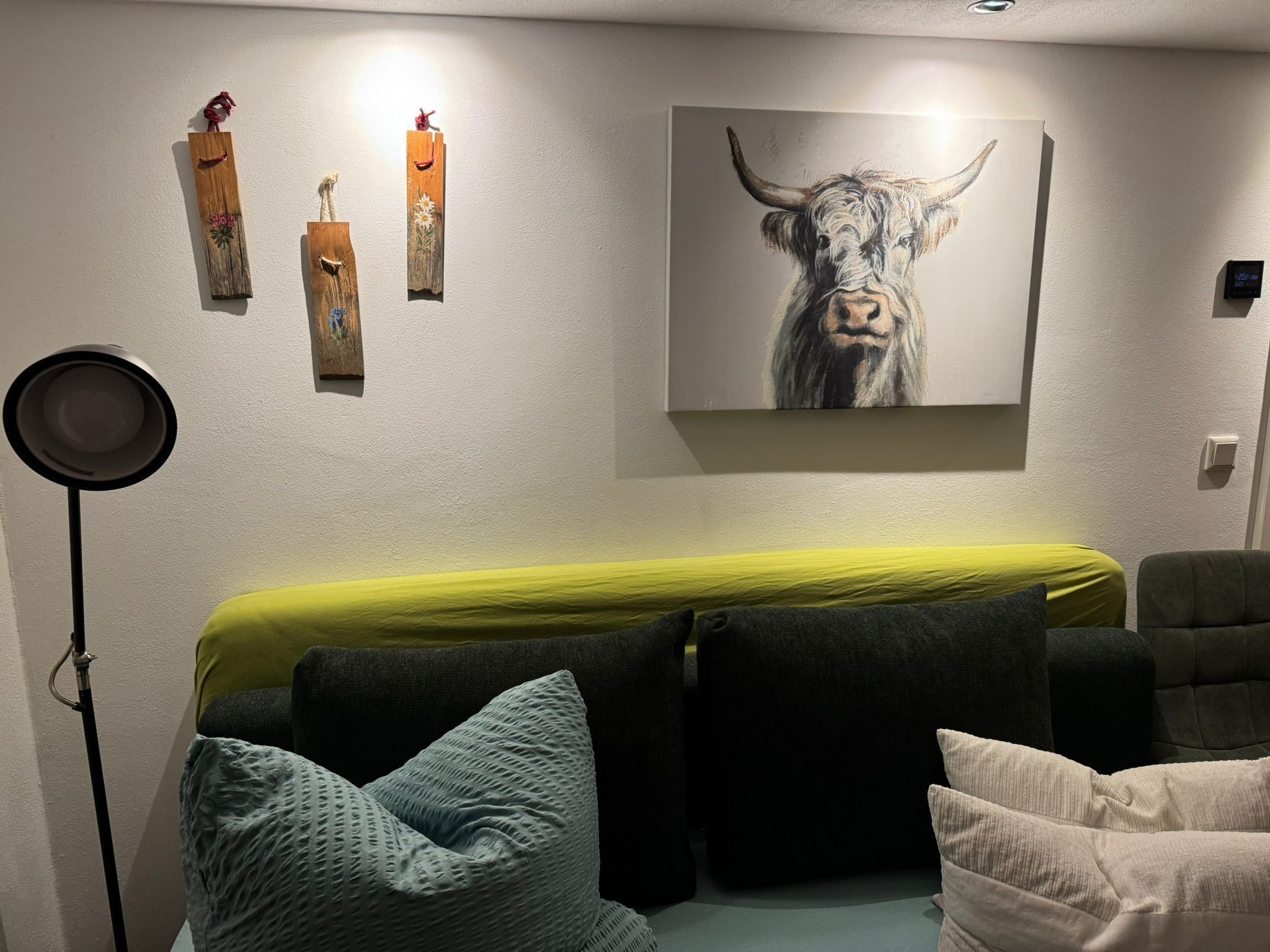 Une pièce avec un lit, une lampe sur pied et un tableau représentant un taureau accroché au mur.