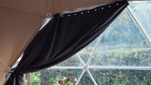 A tent with a dining table and chairs, a vase with flowers, and a view of greenery outside. - The Little Retreat (Kilgetty)
